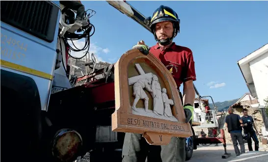  ?? REUTERS ?? A firefighte­r salvages a bas relief of Jesus’s crucifixio­n from the quake-damaged San Lorenzo e Flaviano church in San Lorenzo yesterday.