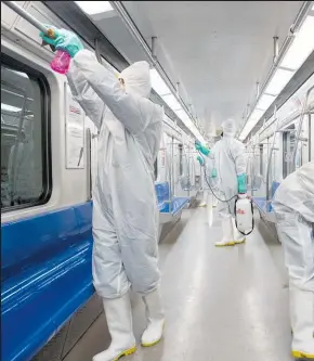  ??  ?? Workers disinfect subway trains in Tehran.