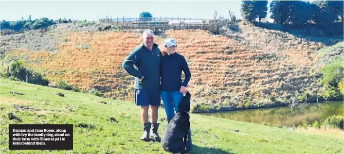 ??  ?? Damian and Jane Roper, along with Ivy the family dog, stand on their farm with O¯ huarai pa¯ i te kohu behind them.