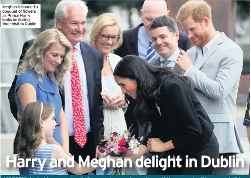  ??  ?? Meghan is handed a bouquet of flowers as Prince Harry looks on during their visit to Dublin
