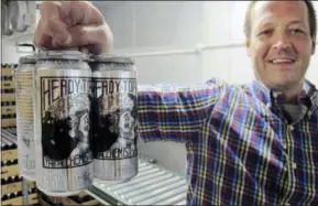  ??  ?? Retail manager Jay Meeks holds a four-pack of Heddy Topper at The Alchemist brewery in Stowe, Vt. The woods of northern New England are luring beer tourists. No discussion of beer in Vermont is complete without The Alchemist, a family run brewery that specialize­s in fresh, unfiltered IPA.