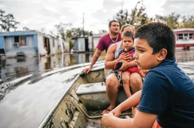  ?? Brandon Bell / Getty Images ?? The Maldonado family travels by boat to their home after it flooded during Hurricane Ida on Tuesday in Barataria, La. Faith-based groups have begun helping communitie­s hit hard by Ida, but the threat of COVID-19 infections still lingers.