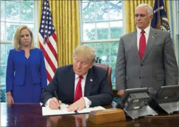  ?? PABLO MARTINEZ MONSIVAIS — THE ASSOCIATED PRESS ?? President Donald Trump signs an executive order to keep families together at the border, but says that the ‘zero-tolerance’ prosecutio­n policy will continue, during an event in the Oval Office of the White House in Washington, Wednesday. Standing behind Trump are Homeland Security Secretary Kirstjen Nielsen, left, and Vice President Mike Pence.