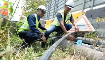  ??  ?? Syabas enforcemen­t officers Fikri Bistamam (right) and Zulazman Mat Jusoh inspect illegal connection­s on treated water supply pipes at a constructi­on site in Kepong. — Bernama photo