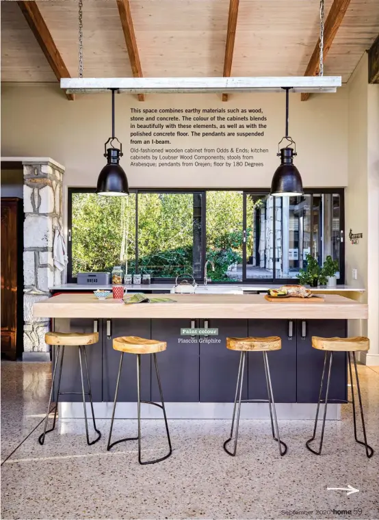  ??  ?? This space combines earthy materials such as wood, stone and concrete. The colour of the cabinets blends in beautifull­y with these elements, as well as with the polished concrete floor. The pendants are suspended from an I-beam.
Old-fashioned wooden cabinet from Odds & Ends; kitchen cabinets by Loubser Wood Components; stools from Arabesque; pendants from Orejen; floor by 180 Degrees