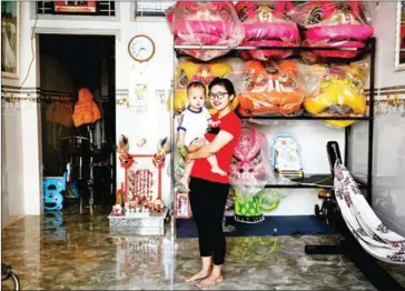  ?? AFP ?? Le Yen Quyen poses with her one-year-old daughter before leaving for practice at the Tu Anh Duong lion and dragon dance school.