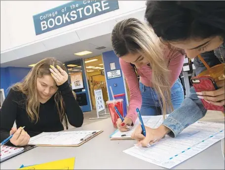  ?? Brian van der Brug Los Angeles Times ?? STUDENTS Genesis Ramirez, 18, Angela Trujillo, 19, and Enya Trujillo, 17, from left, observe National Voter Registrati­on Day at College of the Canyons in Santa Clarita by registerin­g to vote ahead of the midterm election. Suburban women increasing­ly favor Democrats.