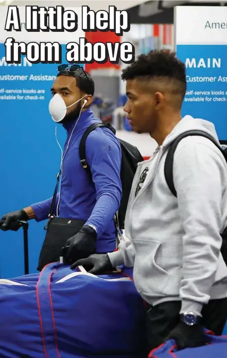  ?? AP FIle ?? LITTLE SPENDING CASH: Toronto Blue Jays minor leaguer Jesus Navarro, left, wears a mask while he prepares to fly home along with his teammates from the Dominican Republic at Tampa Internatio­nal Airport in Tampa on March 15.