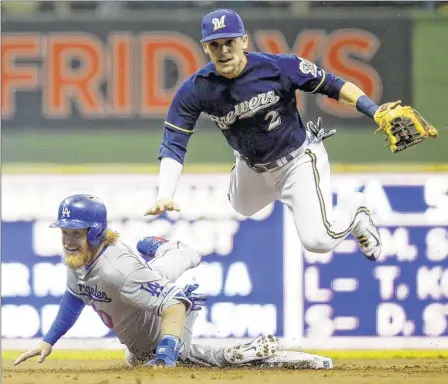  ??  ?? The Brewers’ Scooter Gennett forces the Dodgers’ Justin Turner out at second base and turns a double play in Wednesday’s game at Miller Park.