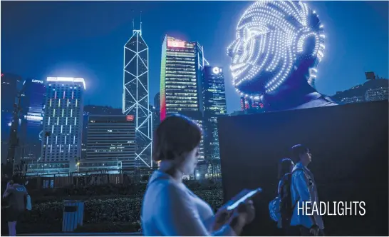  ?? Picture: AFP ?? People walk past Talking Heads by Viktor Vicsek of Hungary during the Hong Kong Pulse Light Festival on Sunday.