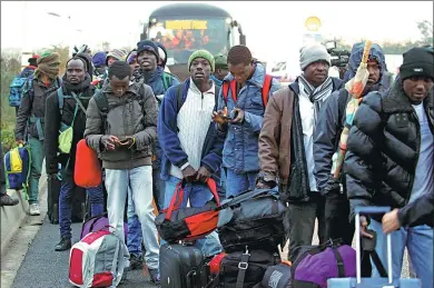  ?? PASCAL ROSSIGNOL / REUTERS ?? Migrants with their belongings queue near buses at the start of the dismantlem­ent of the camp called the “Jungle” in Calais, France, on Monday.