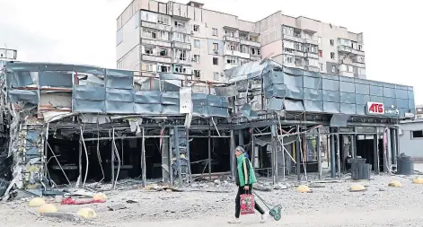  ?? ?? DEVASTATIO­N: A resident walks past buildings wrecked by shelling in the besieged southern city of Mariupol.