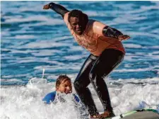  ?? ?? Mutee Alghaffaar,
17, a Surf Club student from Mission High School
in San Francisco, surfs with assistance
from instructor Forest Lowry
from City Surf Project at Linda Mar Beach in Pacifica in February.