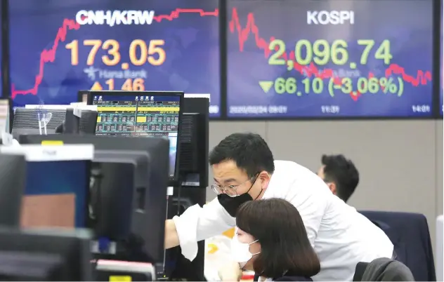  ?? Associated Press ?? ↑
Currency traders wear face masks as they watch monitors at the foreign exchange dealing room in Seoul on Monday.