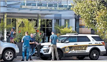  ?? GENE J. PUSKAR/AP ?? Pittsburgh police gather Sunday outside an apartment building where three people were found dead before dawn.