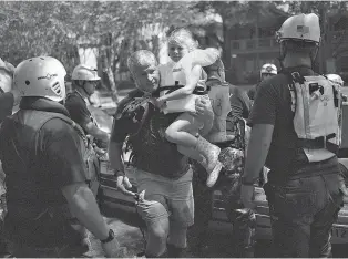  ?? JOHN TAGGART/FOR THE WASHINGTON POST ?? Ken Jacobs carries 5-year-old Astrid Galperin from a rescue boat Thursday. Jacobs, the operations director for a kayak tour and rental business in Houston, was one of many everyday citizens who played a role in rescue efforts.