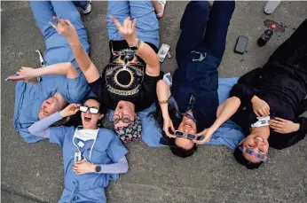  ?? KAILA JONES/AMERICAN-STATESMAN ?? Hospital personnel at Dell Seton Medical Center in Austin cheer during the early stages leading up to the totality of the solar eclipse Monday from the top floor of the hospital’s parking garage.