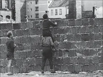  ?? Werner Kreusch Associated Press ?? WITH THE help of a friend, a boy in Wedding, West Berlin, catches a glimpse of East Berlin in August 1961. Germans on Saturday will mark the peaceful end of the Berlin Wall on Nov. 9, 1989, with major celebratio­ns.