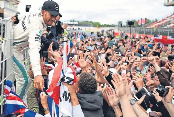  ?? Picture: Getty. ?? Lewis Hamilton celebrates with fans on the pit wall after his victory in Barcelona.