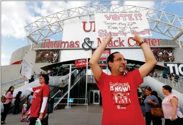  ?? ASSOCIATED PRESS ?? UNION ORGANIZERS ANGIE QIN (LEFT) AND DAVID SABA HOLD SIGNS as members of the Culinary Workers Union, Local 226, file into a university arena to vote on whether to authorize a strike Tuesday in Las Vegas. A potential strike would affect 34 casinohote­ls.