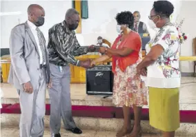  ?? (Photos: Gregory Bennett) ?? Ucal Sinclair (second from left) receives the key to his dwelling from Wendy Litchmore at the Wesley Methodist Church in Mandeville last Sunday. Looking on are councillor for the Mandeville Division, Jones Oliphant, and Gloria Rubie.