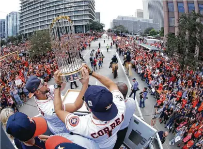  ?? Karen Warren / Houston Chronicle ?? World Series MVP George Springer, left, and Carlos Correa hold up the championsh­ip trophy for all to see during the Astros’ parade Friday through downtown Houston.