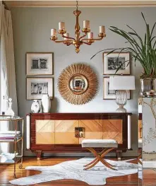  ?? Jeff McNamara ?? A gold-leaf soleil mirror is flanked by French engravings hung over a credenza bearing vintage ceramic pieces.