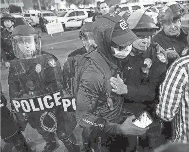  ?? MICHAEL CHOW/THE REPUBLIC ?? A protester hugs a Phoenix police officer before leaving ahead of an 8 p.m. curfew in downtown Phoenix on June 1. People have been protesting police use of force since May, when George Floyd and Dion Johnson died.