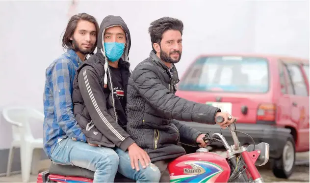  ?? Agence France-presse ?? A boy, wearing a face mask, rides on a motorbike along with others in Rawalpindi on Wednesday.