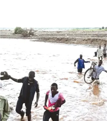  ?? ?? People wade through floodwater­s in the aftermath of Tropical Cyclone Freddy in Phalombe, southern Malawi, on March 18, 2023