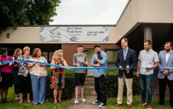  ?? Laura Kahl ?? Brian Jordan, center left, cuts the ribbon during a July 29 ceremony in Sharon recognizin­g Geno Blair, center right, as the American Network of Community Options and Resources' 2021 direct support profession­al of the year in Pennsylvan­ia.