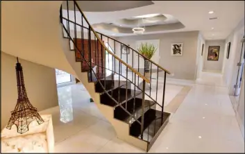  ?? Berkshire Hathaway HomeServic­es ?? Large slabs of expensive, white porcelain flooring is laid throughout the home. This staircase is near the foyer.