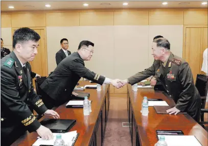  ??  ?? South Korea Defense Ministry South Korean army Col. Cho Yong-geun, left, shakes hands with North Korean counterpar­t Om Chang Nam during a meeting Monday in Paju, South Korea.