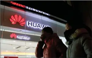  ?? The Associated Press ?? BEIJING: Women walk past a Huawei retail shop Thursday in Beijing. China on Thursday demanded Canada release a Huawei Technologi­es executive who was arrested in a case that adds to technology tensions with Washington and threatens to complicate trade talks.