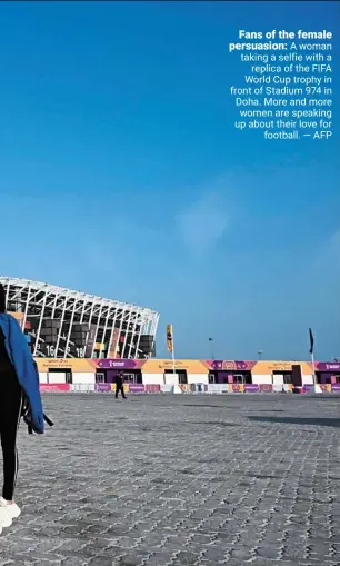  ?? ?? Fans of the female persuasion: a woman taking a selfie with a replica of the FIFA World Cup trophy in front of Stadium 974 in doha. more and more women are speaking up about their love for football. — AFP