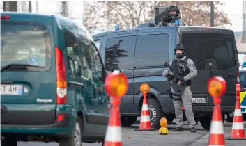  ??  ?? Heavily armed German police officers check cars at the border between Strasbourg, France, and Kehl, Germany, on Thursday when French security forces try to catch the suspected shooter dead or alive, two days after an attack near Strasbourg’s Christmas market. SebaStIan Gollnow/DPa VIa aP