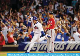  ?? — AFP ?? CHICAGO: David Bote #13 of the Chicago Cubs celebrates his walk-off grand slam as Ryan Zimmerman #11 of the Washington Nationals looks on at Wrigley Field on Sunday in Chicago, Illinois. The Chicago Cubs won 4-3.