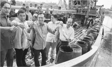  ??  ?? Ahmad Shabery (third left) showing the fish after a meet-and- greet session with Kelantan fishermen. — Bernama photo