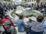 ??  ?? Fascino Un gruppo di turisti in piazza di Spagna intorno alla Fontana della Barcaccia