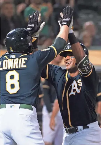  ?? KELLEY L. COX/USA TODAY SPORTS ?? Athletics second baseman Jed Lowrie high-fives DH Khris Davis after one of his 40 homers this season.
