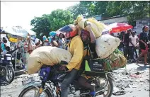  ?? RALPH TEDY EROL / REUTERS ?? People ride on a motorcycle in Port-au-Prince on Saturday, the day 17 foreigners were kidnapped in Haiti.