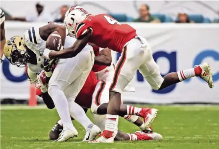  ?? AL DIAZ adiaz@miamiheral­d.com ?? Hurricanes defensive back Jaquan Johnson rips the ball away from Panthers running back Darrin Hall, who fumbles in the first quarter on Saturday at Hard Rock Stadium. UM’s defense shut down Pittsburgh with six sacks and 14 tackles for loss and held its offense to 200 total yards.