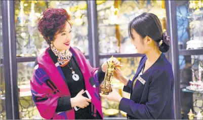  ?? XINHUA ?? A tourist buys bronzeware made in Pakistan at the Grand Bazaar in Urumqi, capital of the Xinjiang Uygur autonomous region.