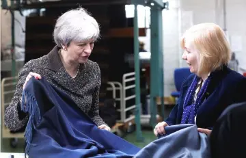  ??  ?? May (left) looks at textiles as she visits textile producers Alex Begg in Ayr, Scotland. — AFP photo