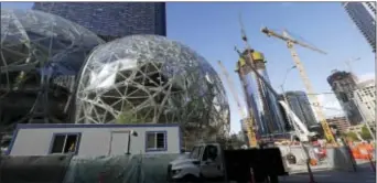  ?? ASSOCIATED PRESS ?? In this Oct. 11, 2017, file photo, large spheres take shape in front of an existing Amazon building, behind, as new constructi­on continues across the street in Seattle. Amazon announced in 2017 it is looking for a home for its second headquarte­rs.