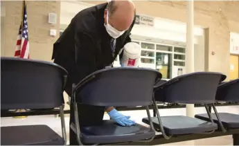  ??  ?? Paul Phillips, branch chief of customer service for U.S. Citizenshi­p and Immigratio­n Services, disinfects seats before a naturaliza­tion ceremony in the South Loop.