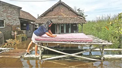 ?? GHOUFUR EKA/JAWA POS ?? LANGGANAN BANJIR: Misina, warga Desa Kalitengah, Kecamatan Porong, menjemur kasur di depan rumahnya yang terendam air kemarin.
