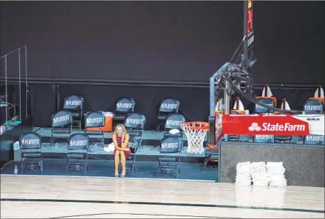  ?? Ashley Landis Associated Press ?? A REPORTER SITS by an empty court in Orlando, Fla., after the Milwaukee Bucks refused to play the Orlando Magic in a playoff game.