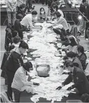  ?? LEE YOUNG-HO Sipa USA/USA TODAY NETWORK ?? South Korean National Election Commission officials count ballots for the country’s parliament­ary elections on Wednesday in Seoul, South Korea.