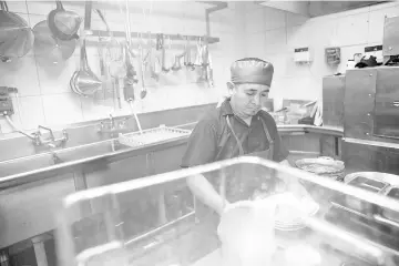  ??  ?? Dishwasher Soc holds plates while working in the kitchen at Caracol in Houston.